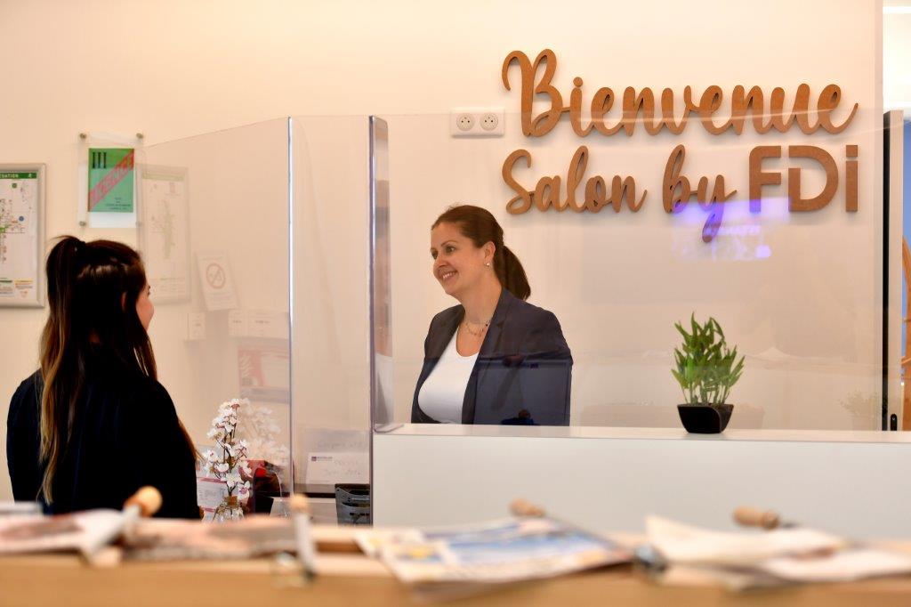une hôtesse accueillant une cliente à l'entrée du salon