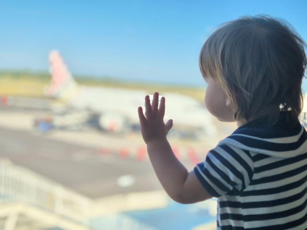 enfant derrrière une vitre avec avion en fond